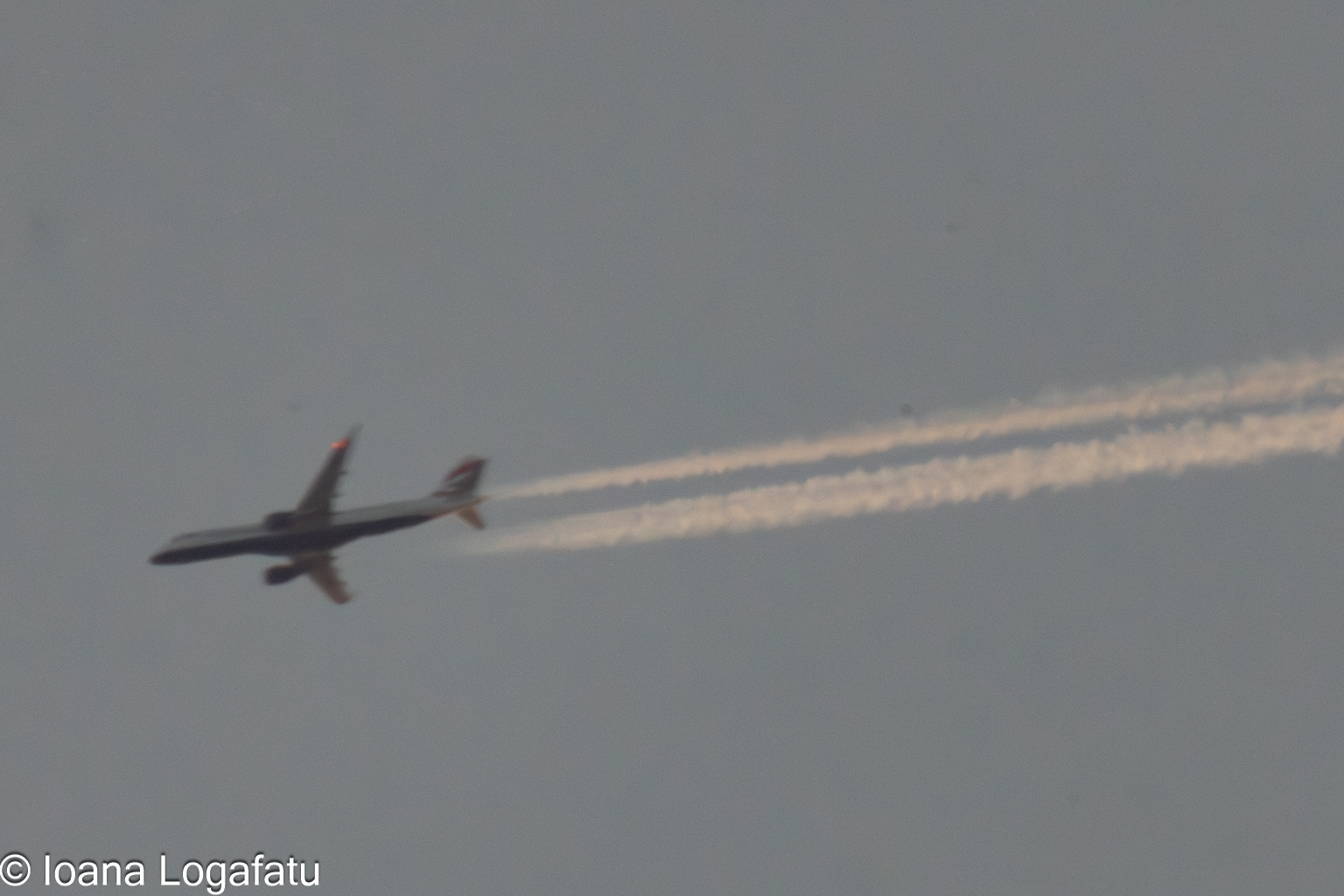 Jet cutting through a clear blue sky above city